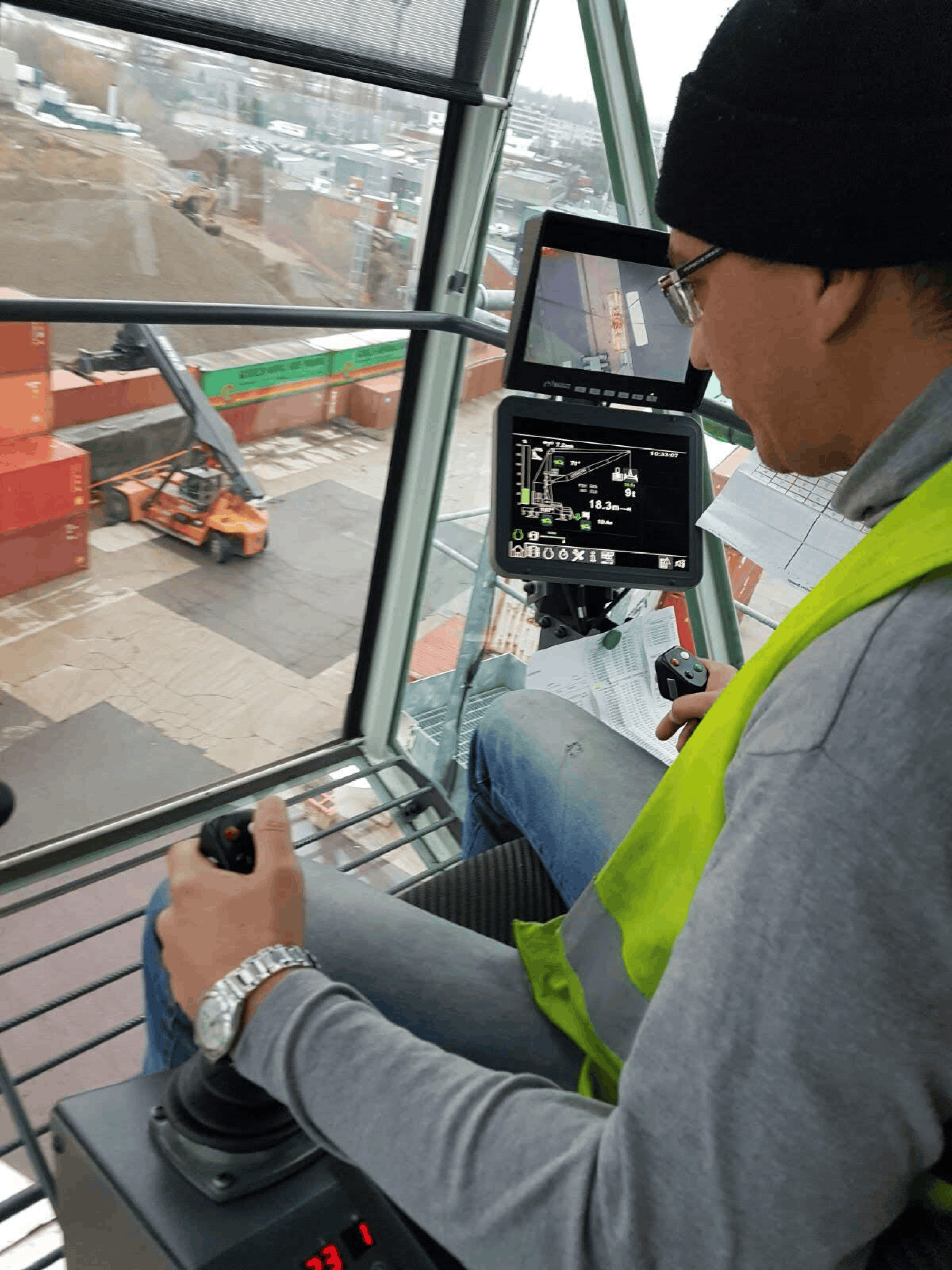 Crane operator at control station monitoring load chart and site operations